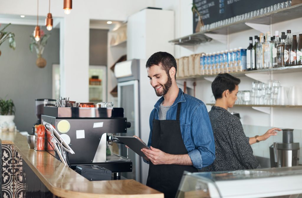 young man using a digital tablet in his coffee shop